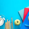 Flat lay background with colorful educational supplies on bright blue background, top view, back to school concept.